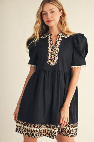 Black babydoll dress with leopard print trim, scalloped edges, and puff sleeves