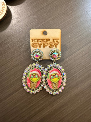 Grinch cameo drop earrings with iridescent rhinestone frames on wooden display card