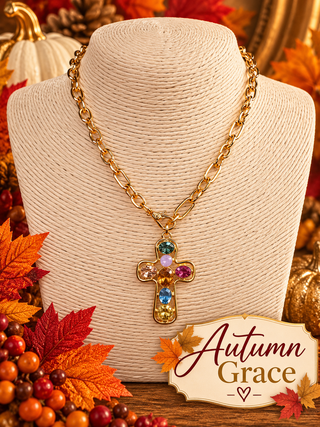 Gold chain necklace with multicolor gemstone cross pendant on jewelry display bust