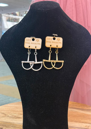 Silver and gold snaffle bit dangle earrings by Pink Panache on black jewelry display