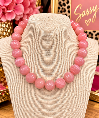 Chunky pink marbled round bead statement necklace displayed on cream jewelry bust
