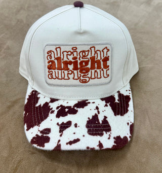 White baseball cap with cow print brim and alright alright alright embroidered patch
