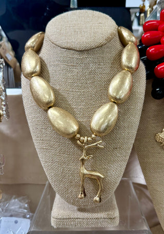 Gold oversized oval bead statement necklace with gold reindeer pendant on display bust