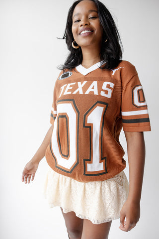 Model wearing burnt orange Texas Longhorns number 01 mesh sweater jersey with white lace skirt