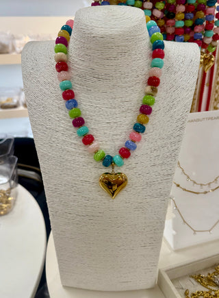 Multicolor glossy beaded necklace with large gold puffy heart pendant on display bust