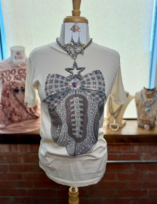 Cream graphic tee with rhinestone-embellished football and jeweled bow print on mannequin