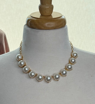 Gold-tone statement necklace with large white faux pearl beads on mannequin