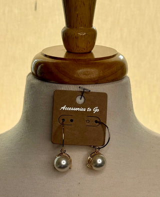 Gold hoop earrings with round white pearl drop and rhinestone cap on display card