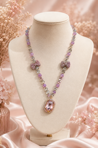 Pink and purple beaded necklace with pavé bow charms and gem pendant on display bust