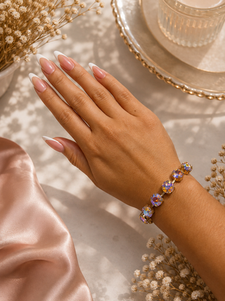 Iridescent crystal tennis bracelet with gold-toned pronged settings on a woman's wrist