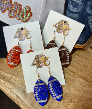 Glitter football-shaped dangle earrings in orange, brown, and blue with rhinestone seam details