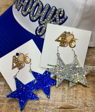 Star-shaped rhinestone dangle earrings in royal blue and crystal silver on display cards