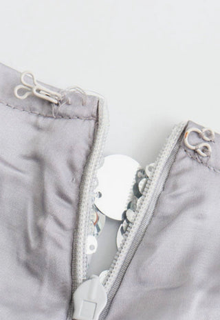 Gray garment interior with silver sequin trim, zipper, and hook-and-eye closures