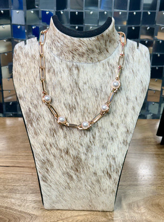 Gold paperclip chain necklace with five pearl cabochon bezel stations on cowhide display
