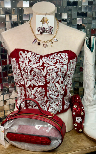 Maroon strapless corset top with white floral embroidery on mannequin bust