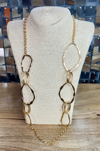 Long gold hammered open-link statement necklace with alternating large oval rings on display bust