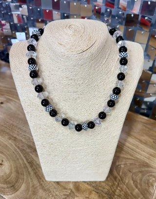 Beaded necklace with black, crystal clear, and black-white checkered round beads on bust display
