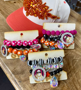 Three stacked beaded bracelet sets in pink, orange, black, and white with rhinestone medallion charms