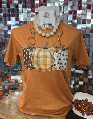 Burnt orange graphic tee with three patchwork-style pumpkins in plaid and polka dot prints