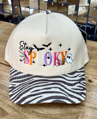 Cream baseball cap with multicolor Stay Spooky embroidery and zebra-stripe print brim