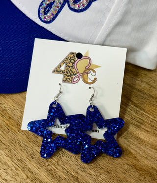 Oversized blue glitter star-shaped dangle earrings with star cut-out on display card