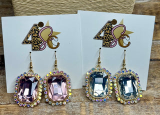 Gold-tone dangle earrings with large pink and clear faceted gemstones framed by iridescent rhinestones