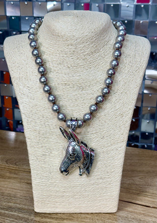 Gray pearl beaded necklace with large silver donkey head pendant on display bust