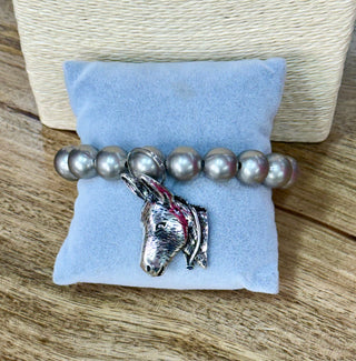 Gray pearl stretch bracelet with silver 3D donkey head charm on velvet display pillow