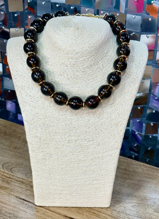Glossy dark brown round bead choker necklace with gold-toned spacers on display bust