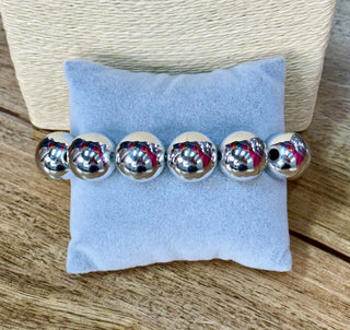Polished silver large round bead stretch bracelet displayed on a gray velvet cushion