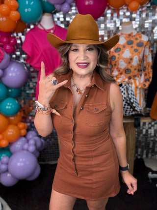 Rust brown sleeveless denim mini dress with snap buttons, worn with matching cowboy hat