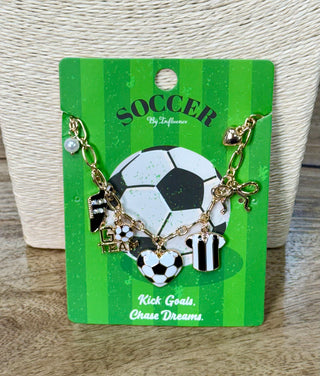 Gold-tone soccer charm bracelet with enamel ball, jersey, and heart charms on green card