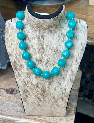 Turquoise round marbled bead necklace with teal cord spacers on cowhide display bust
