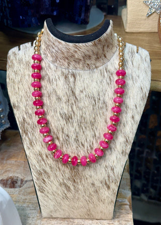 Pink rondelle and gold accent beaded necklace displayed on cowhide jewelry bust