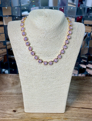 Blush pink crystal tennis necklace with gold prong settings on ivory display bust