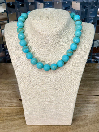 Single-strand turquoise beaded necklace with large polished round beads on display bust