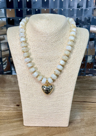 Ivory beaded necklace with gold spacers and polished gold puffy heart pendant on display bust