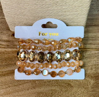 Set of five stackable gold champagne beaded stretch bracelets on gift card packaging
