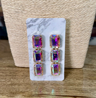 Iridescent AB crystal triple drop earrings with gold-tone prong settings on marble display card