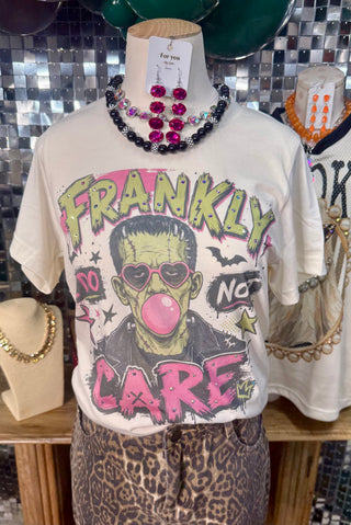 White graphic tee with Frankenstein pop-art print reading Frankly I Do Not Care with rhinestone accents