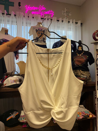 Cream sleeveless twist-front crop top with gold zipper and pearl necklace detail